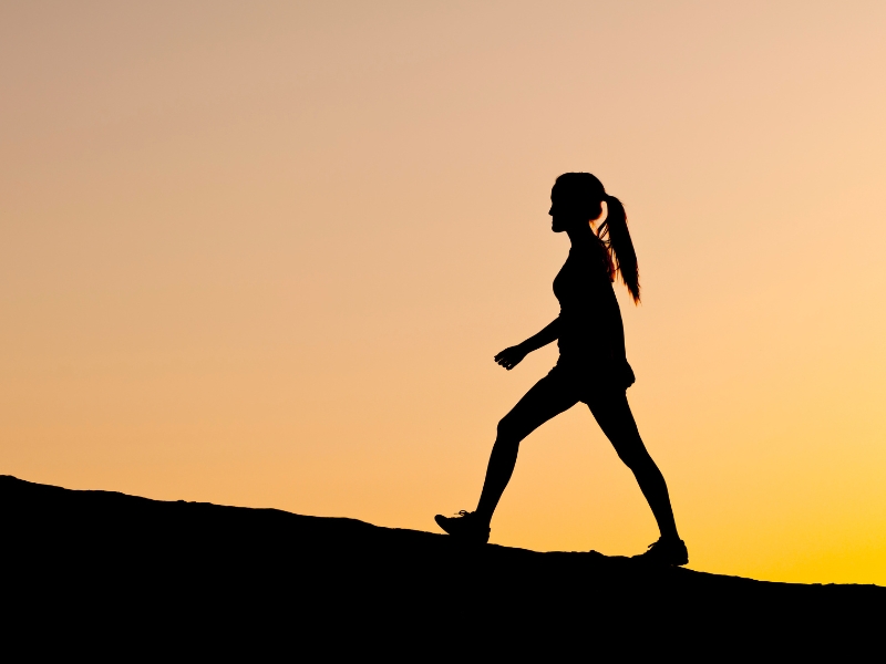 A person walking outdoors, following a walking for weight loss plan.