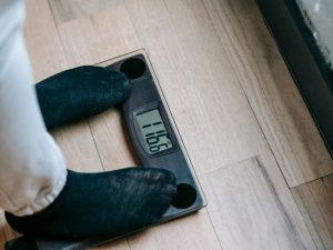 Person checking weight on scale highlighting the importance of avoiding worst foods for slow metabolism.