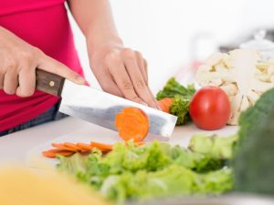 Hands chopping vegetables, preparing a healthy meal to maintain optimal meal timing and nutritional balance.